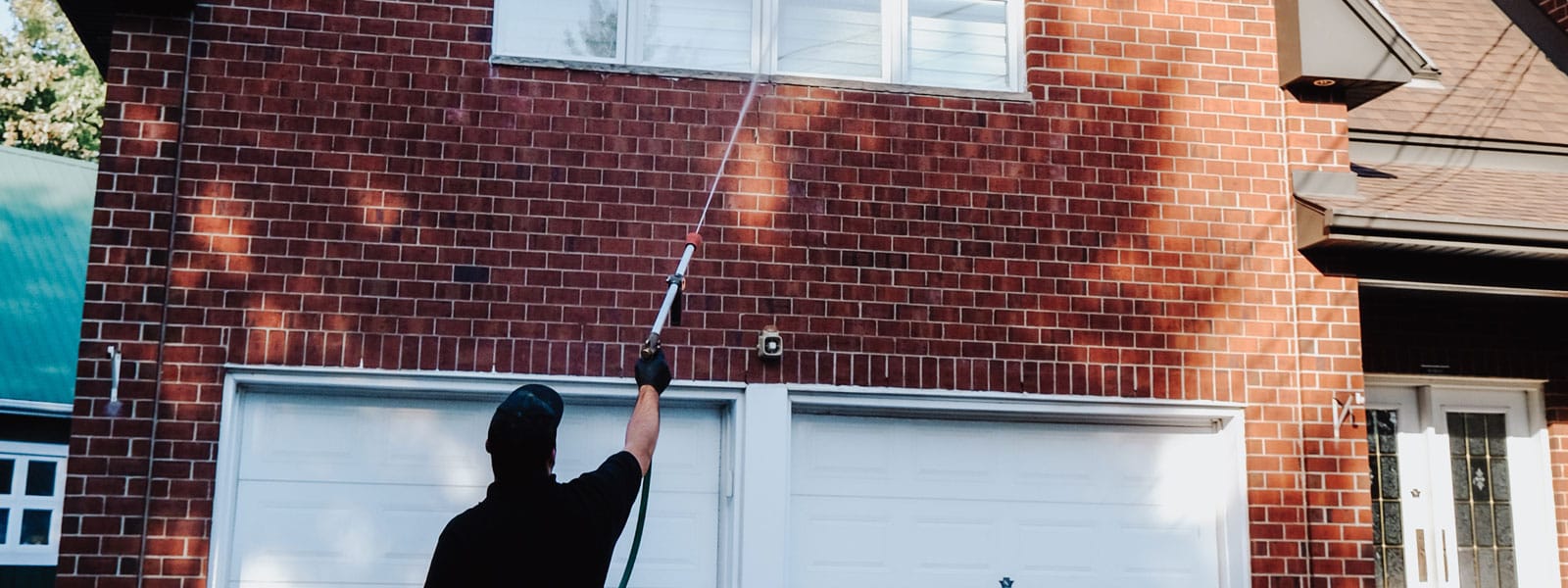 Exterminateur arrosant les corniches d'une maison.