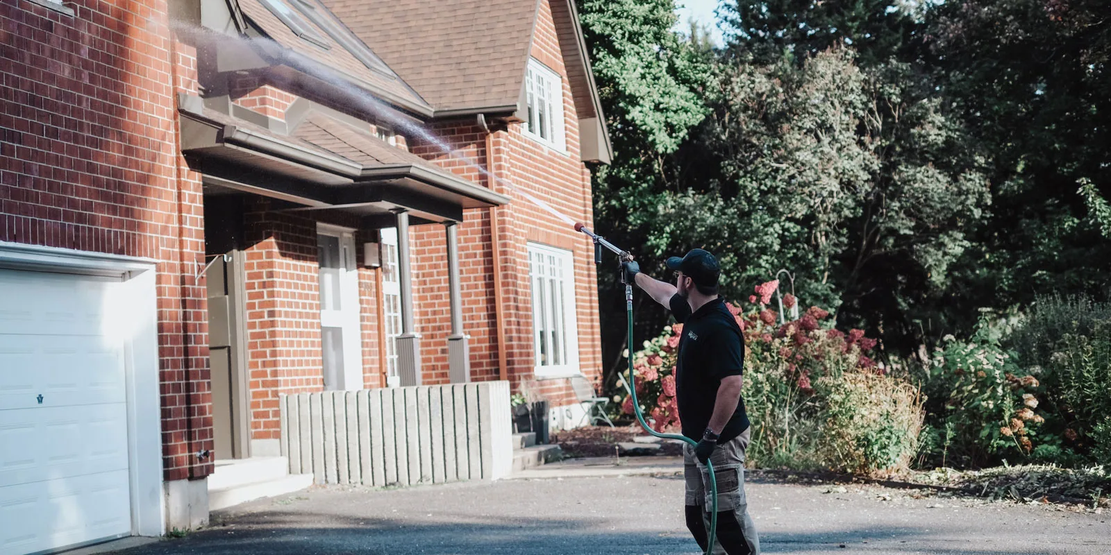 Exterminateur arrosant le devant d'une maison.